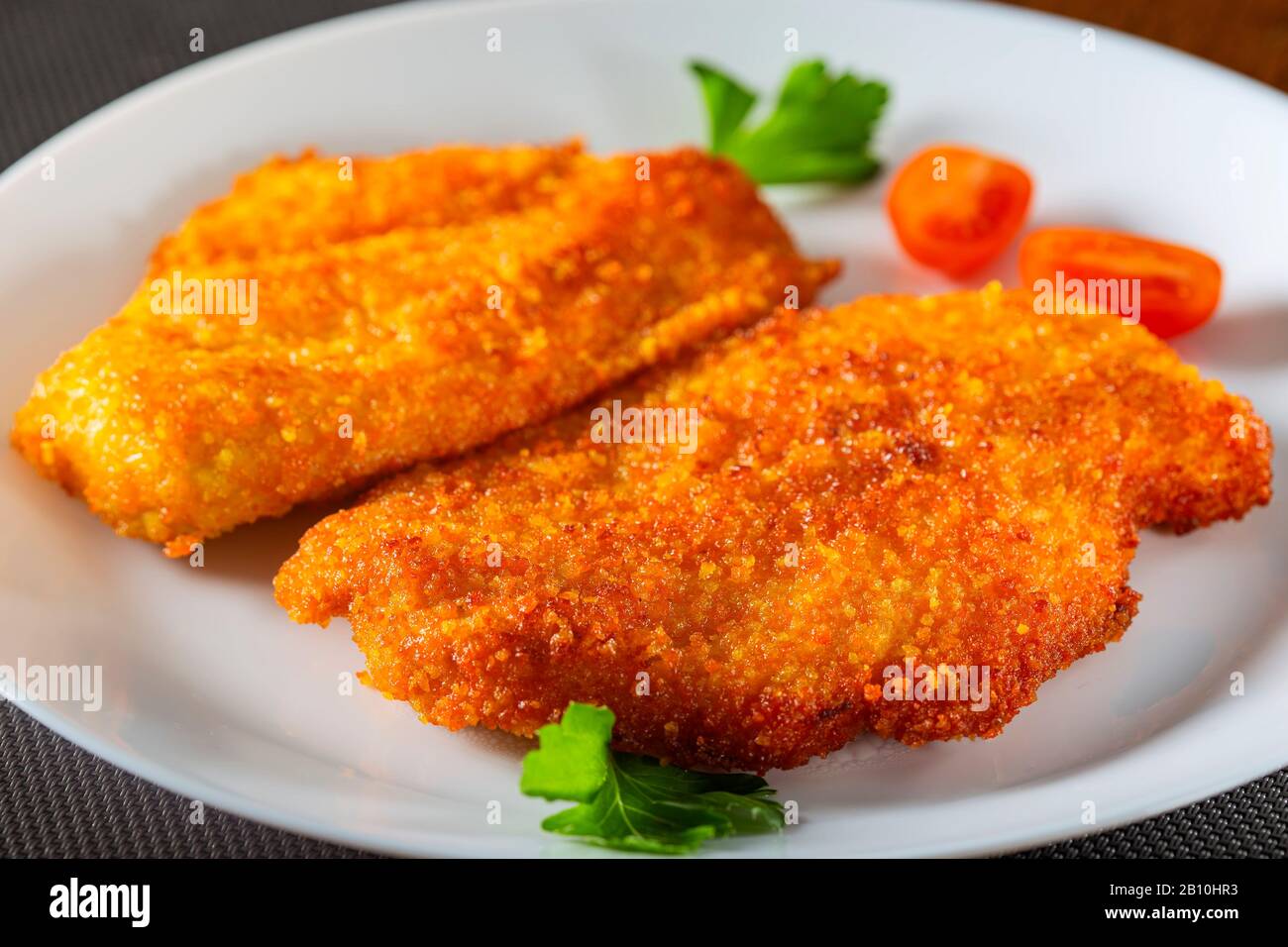 Chicken schnitzel on plate with herbs Stock Photo