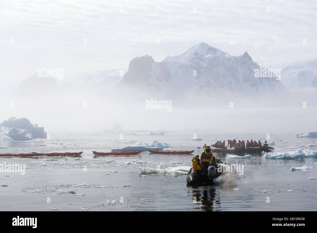Zodiacs from an expedition cruise ship cruising around the Yalour Islands, Wilhelm Archipelago, Antarctica in misty conditions. Stock Photo