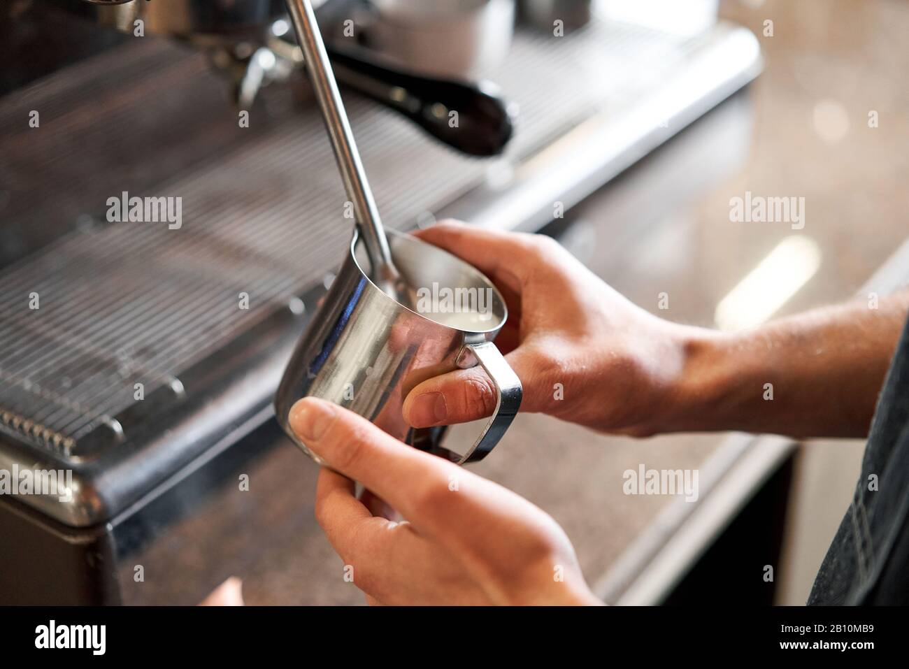 small business, people and service concept. Bartender in apron with holder and tamper preparing coffee at coffee shop Stock Photo