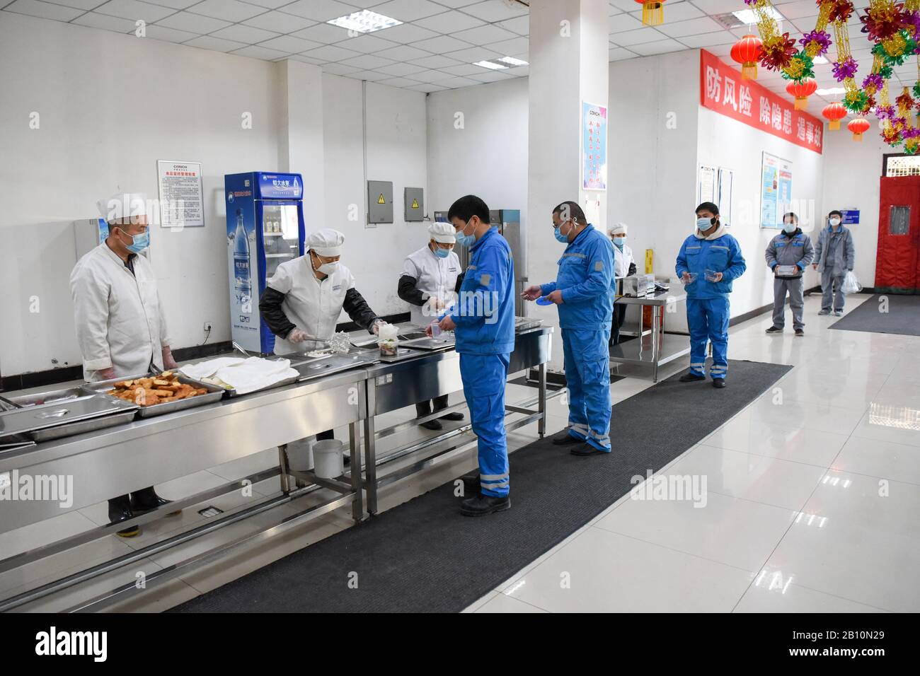 Urumqi, China's Xinjiang Uygur Autonomous Region. 22nd Feb, 2020. Staff members of the Wuhu Conch Profiles and Science Co., Ltd. queue up at a canteen for meals in Urumqi, northwest China's Xinjiang Uygur Autonomous Region, Feb. 22, 2020. Some companies in Urumqi have resumed production amid strict prevention and control measures against the novel coronavirus. Credit: Ding Lei/Xinhua/Alamy Live News Stock Photo