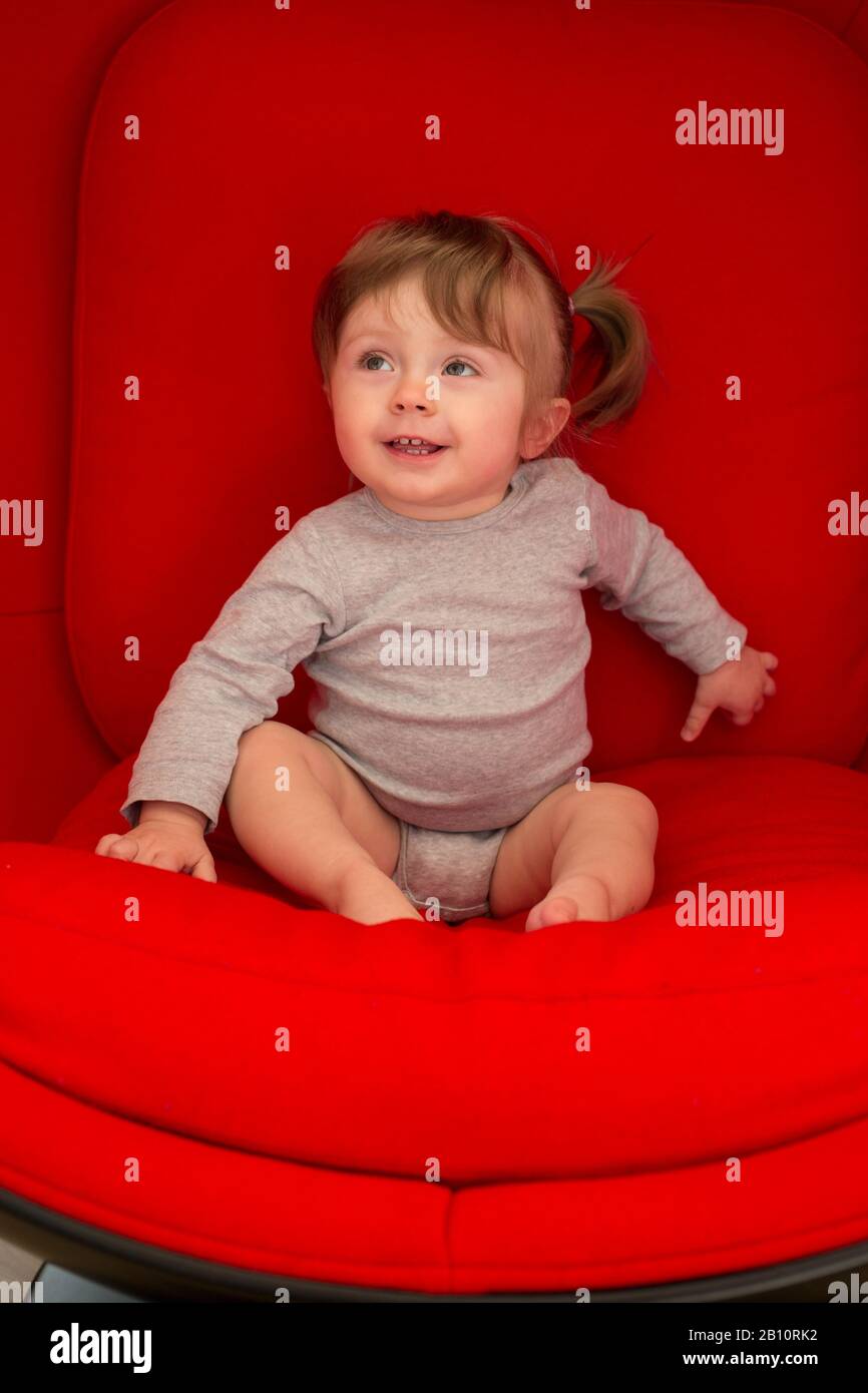 Little cute girl sits on couch Stock Photo Alamy