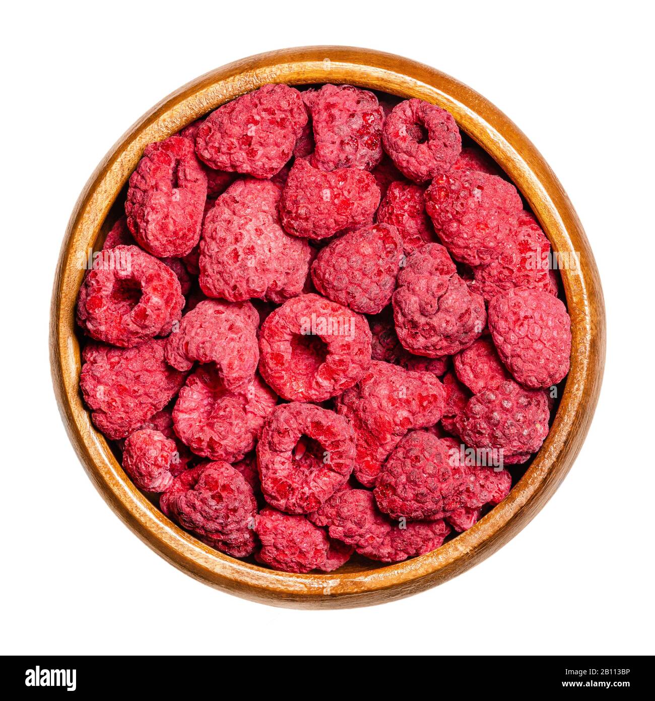 Dried whole raspberries in a wooden bowl. Edible, ripe, red and sweet fruits of Rubus idaeus, the cultivated European raspberry. Closeup, from above. Stock Photo