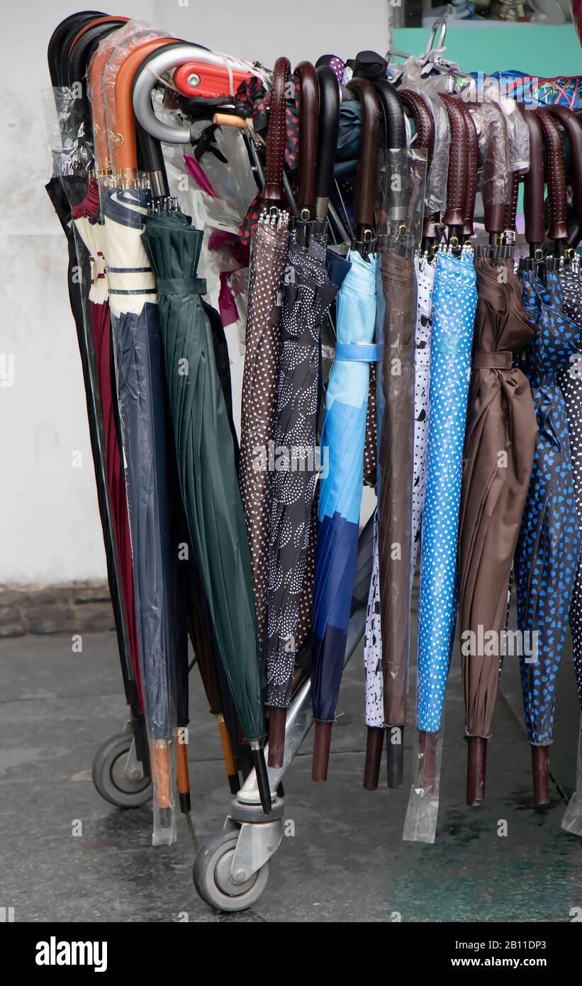 Many different curve handle umbrellas displayed for sale on a street on a rainy day Stock Photo