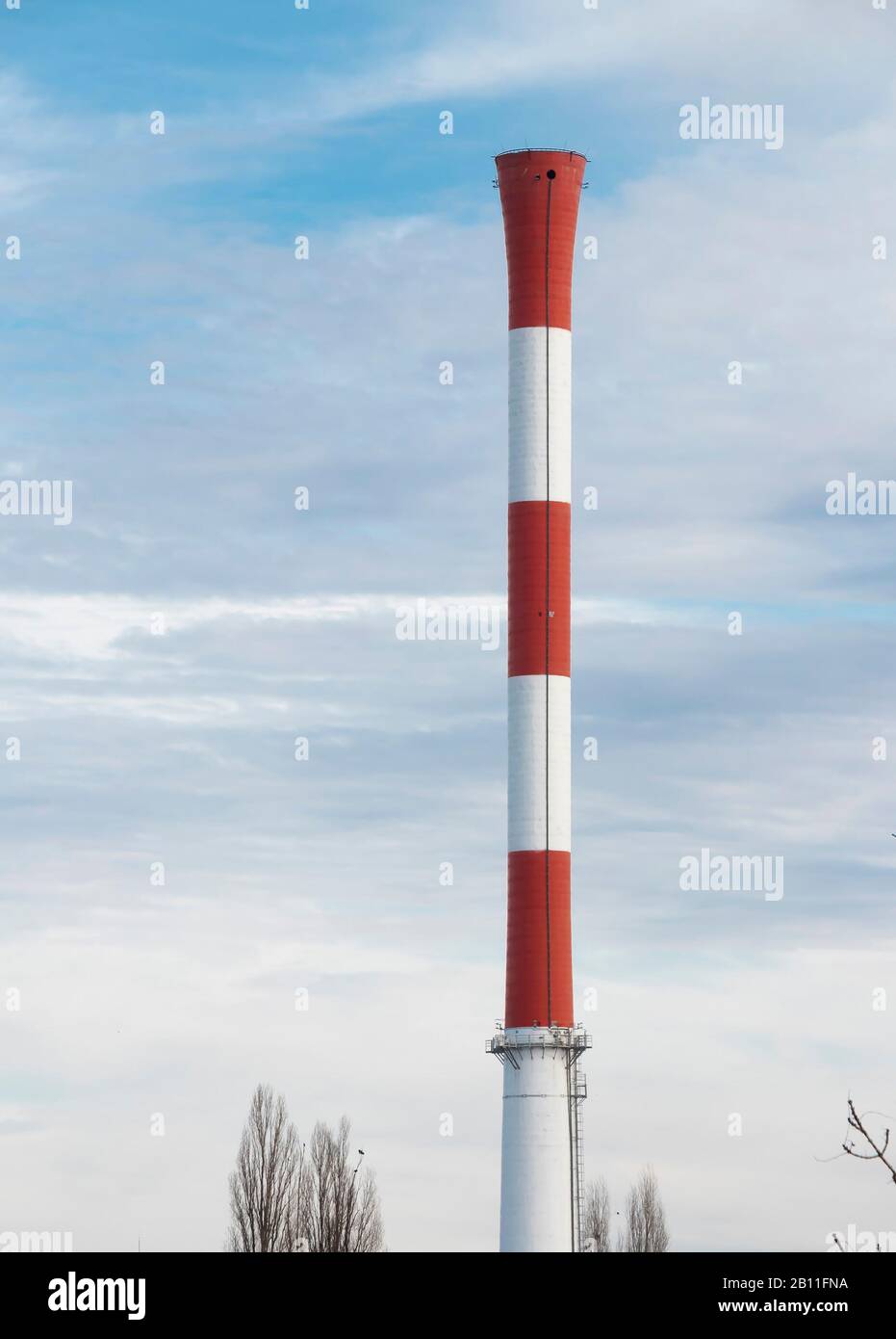 Smokeless chimney smokestack in red and white stripes, , in an industrial part of the city, on a sunny winter day Stock Photo