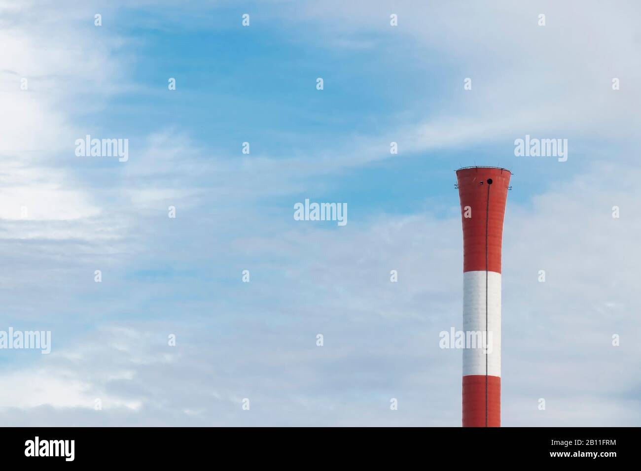Close up of a smokeless chimney smokestack in red and white stripes on a sunny day against the blu sky Stock Photo