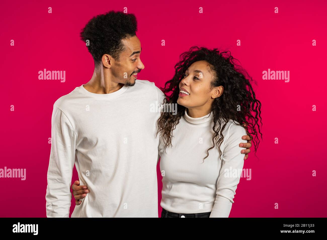 Portrait of young african american couple on red studio background ...
