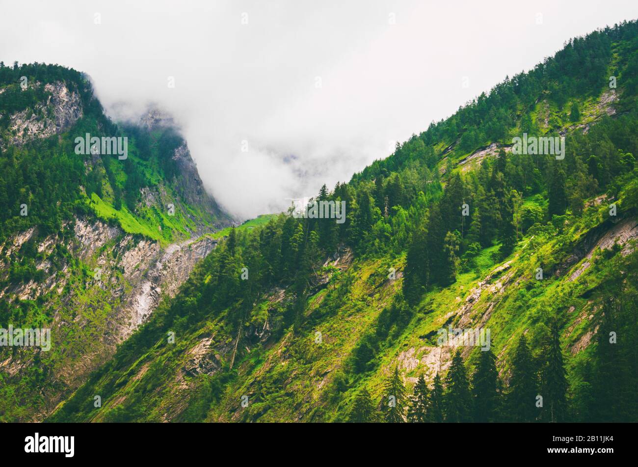 Scenic mountain slope with overhanging clouds. Mountain source water flowing through the rocks. Stock Photo