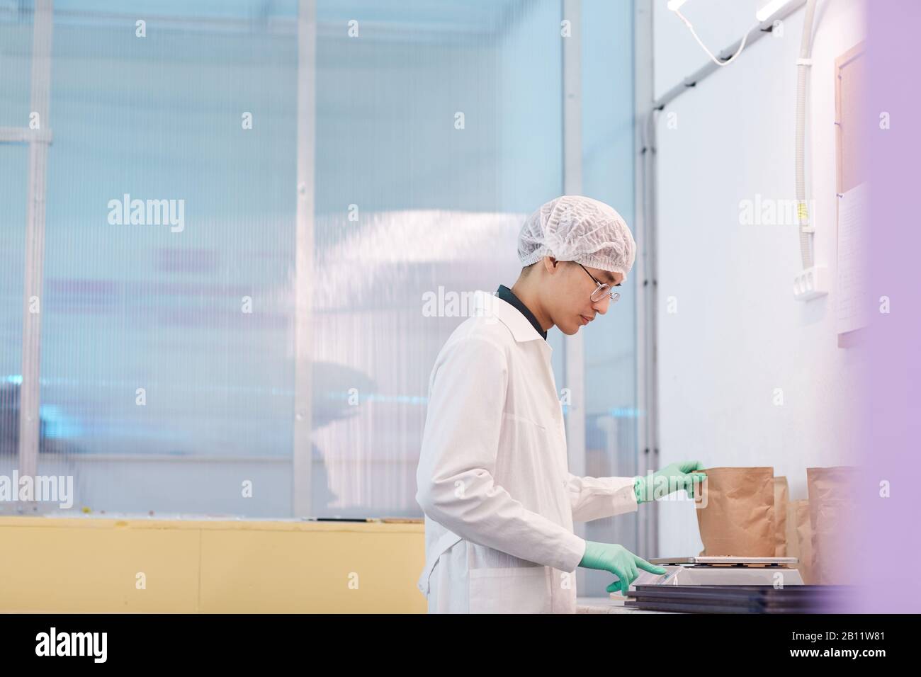 Asian scientist in white coat weighing package in the laboratory Stock Photo