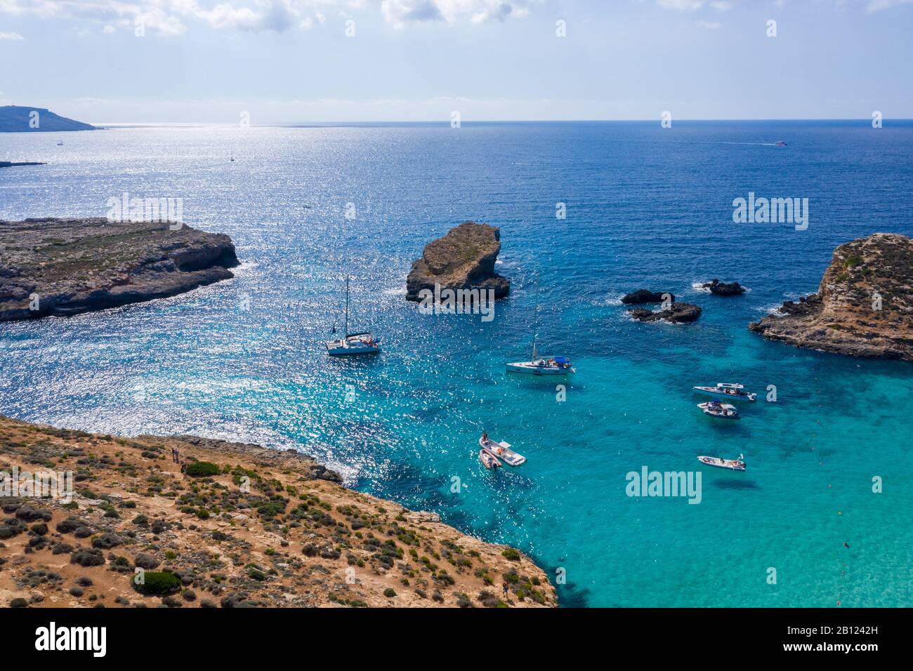 Aerial drone view Comino, Malta Tourists crowd at Blue Lagoon to enjoy the clear turquoise water with clear blue sky and boats in summer Stock Photo