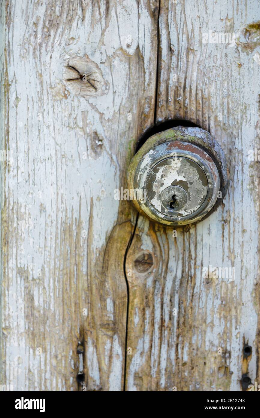 Old Yale cylinder lock in weathered, painted wooden door, reused as chicken shed door. Stock Photo