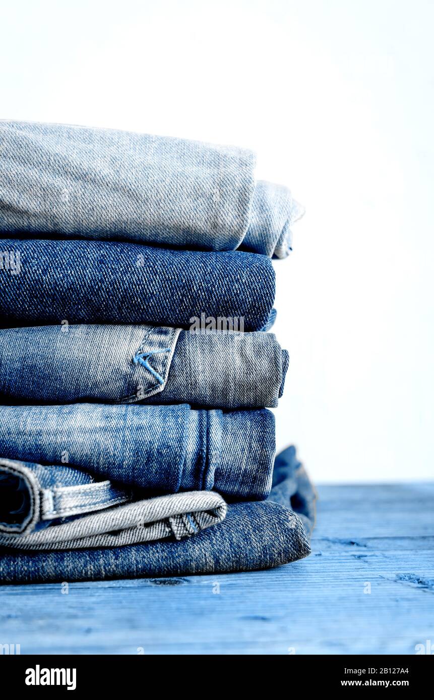 Classic blue color jeans stacked on a wooden table. Denim textiles clothing  background pile concept. Classic blue color of the year 2020 concept. Copy  Stock Photo - Alamy