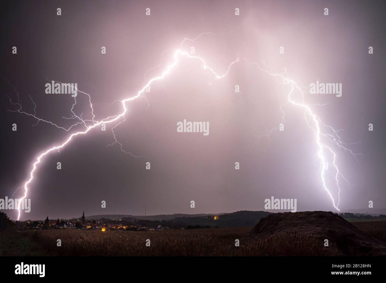 Branched lightning bolts behind the city of Grünberg, Hessen, Germany Stock Photo