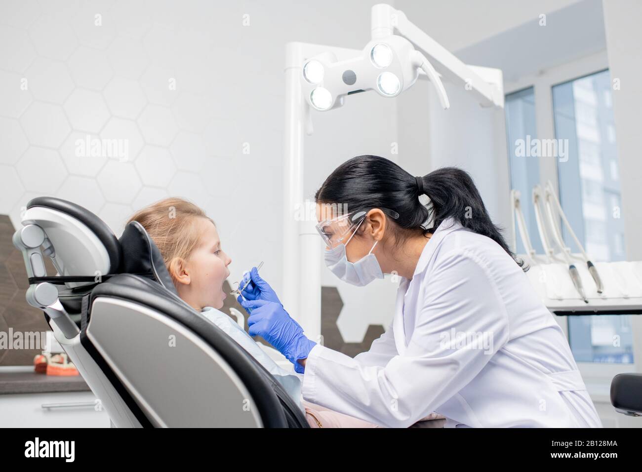 Young dentist using dental hook and mirror during oral