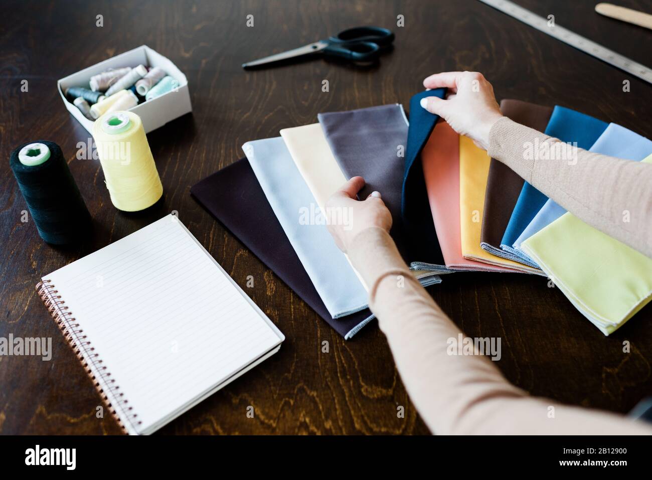 Hands of female fashion designer looking through textile samples on table Stock Photo