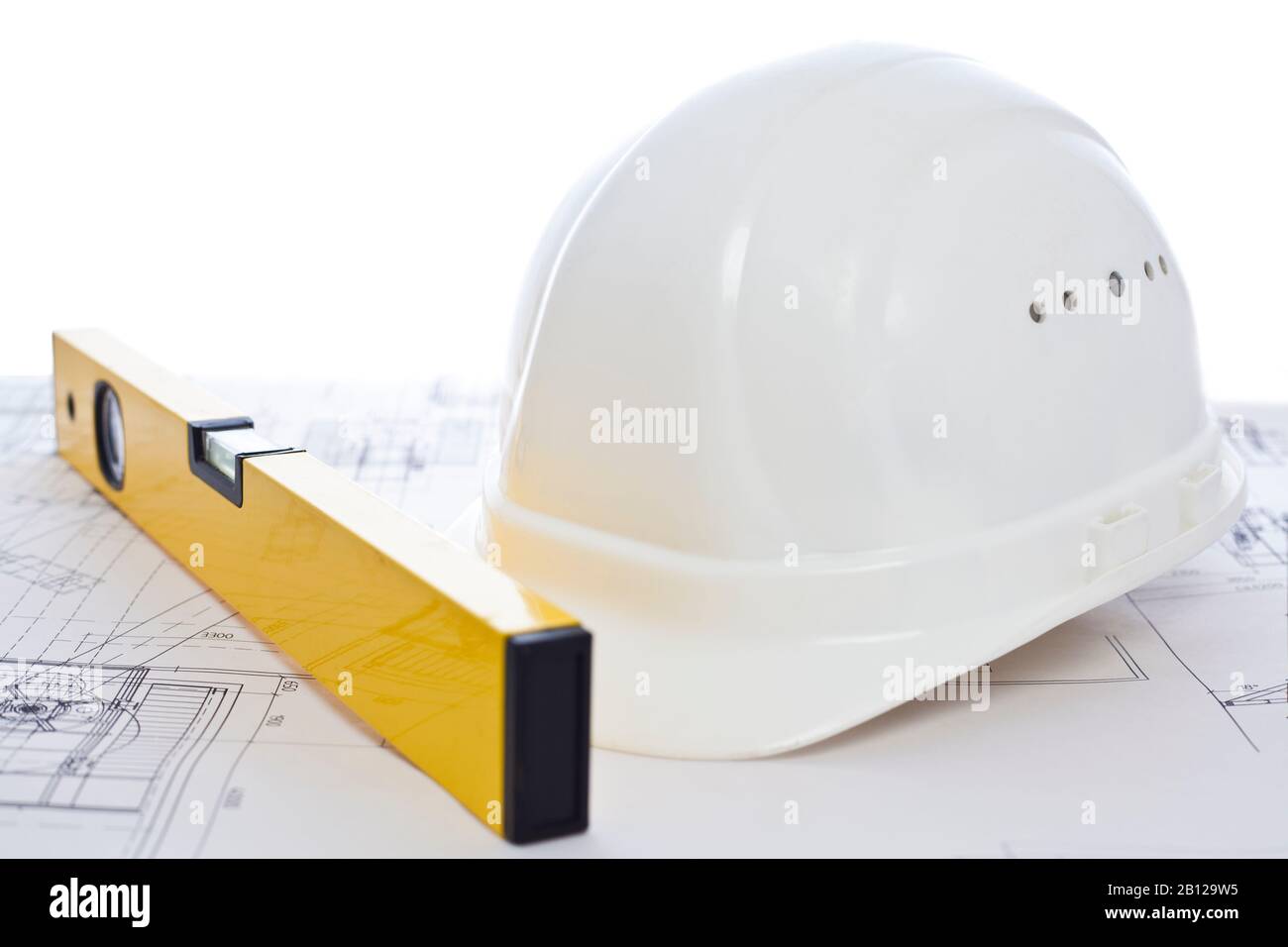 White hard hat and yellow level lying on construction plan - white background Stock Photo