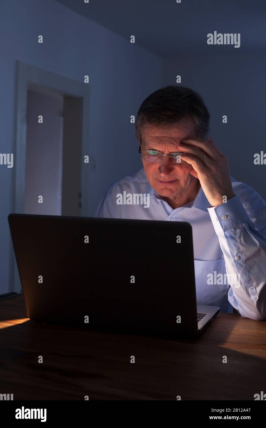 Pensive man working with laptop by night Stock Photo