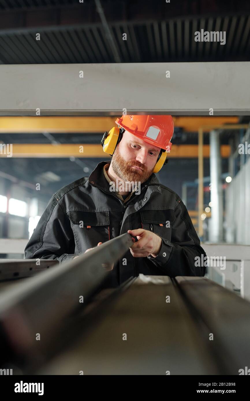 Young engineer of industrial plant looking at one of iron details Stock Photo