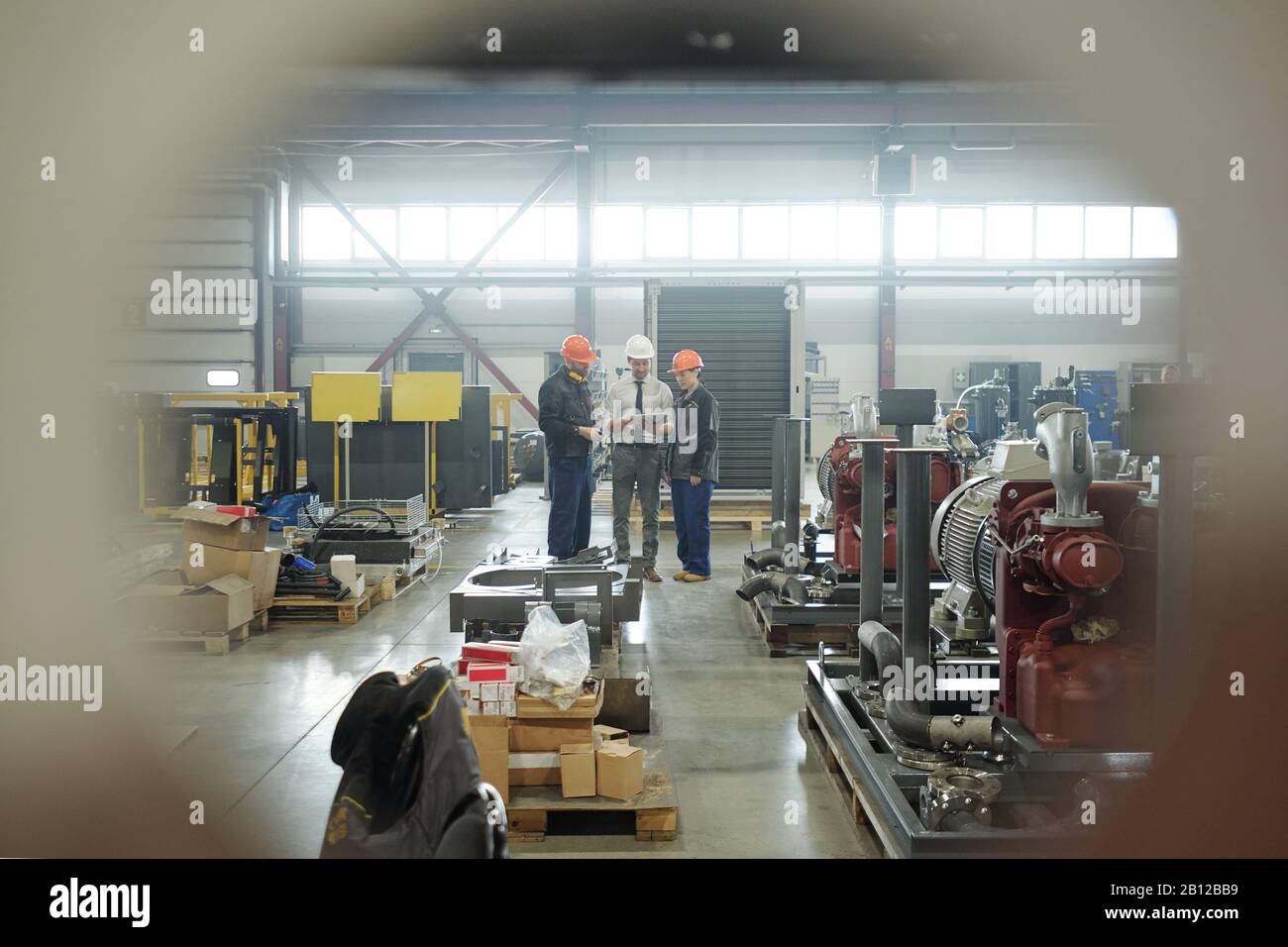 Three engineers of industrial plant discussing technical sketch in touchpad Stock Photo
