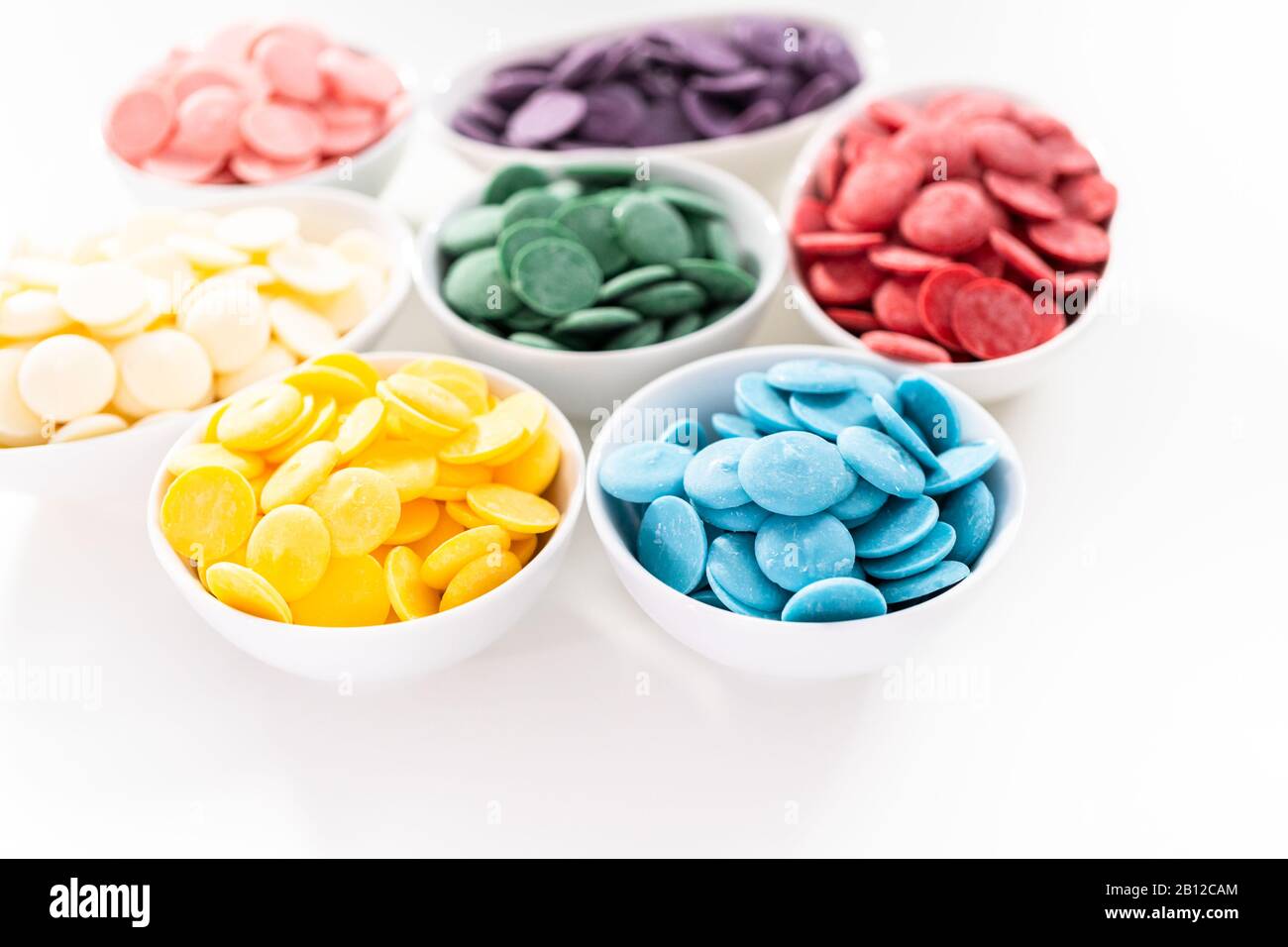 Rainbow colors of round chocolate chips in a white bowls for melting