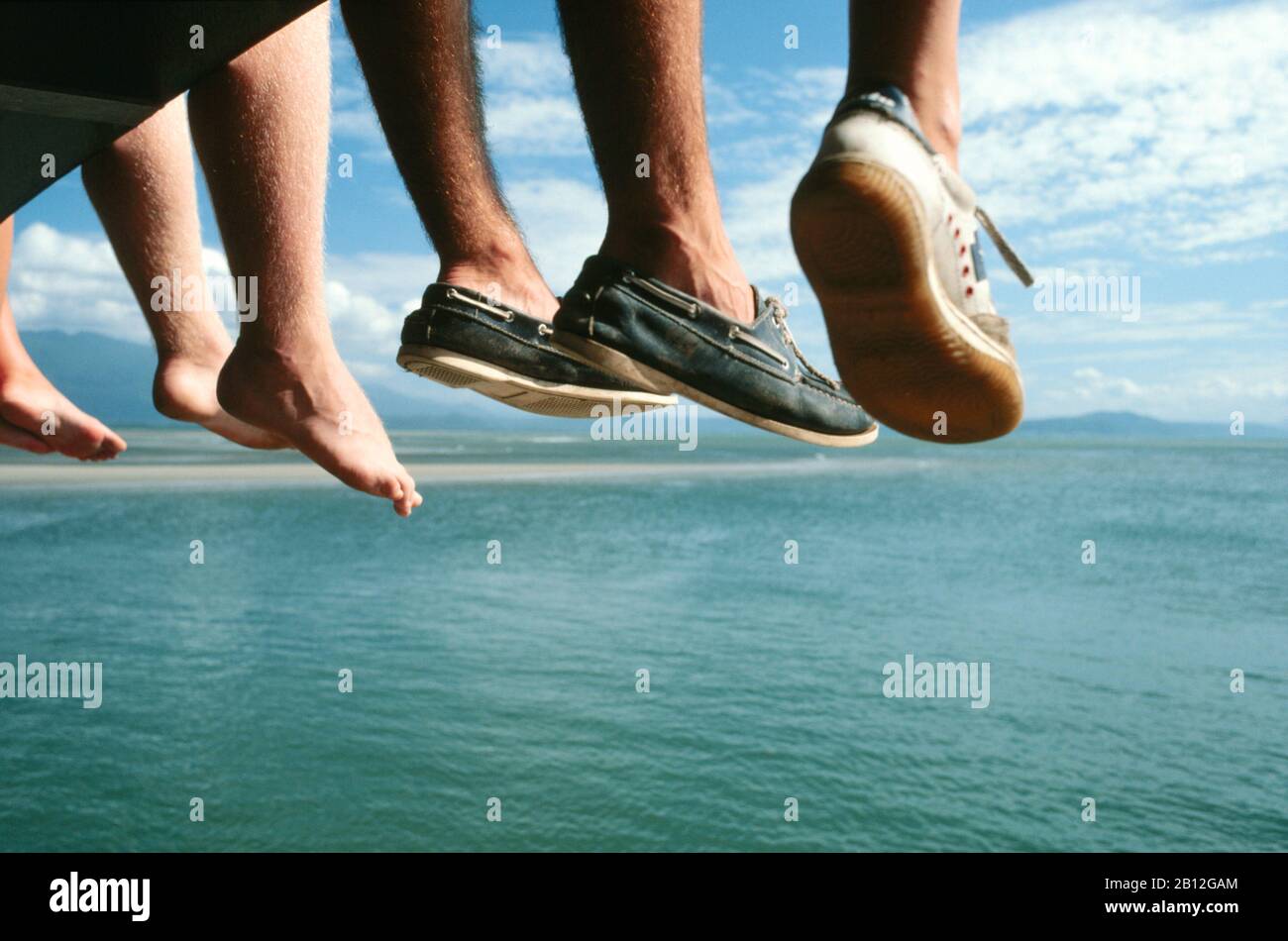 Australia, tourists with their feet hanging down from boat, enjoying