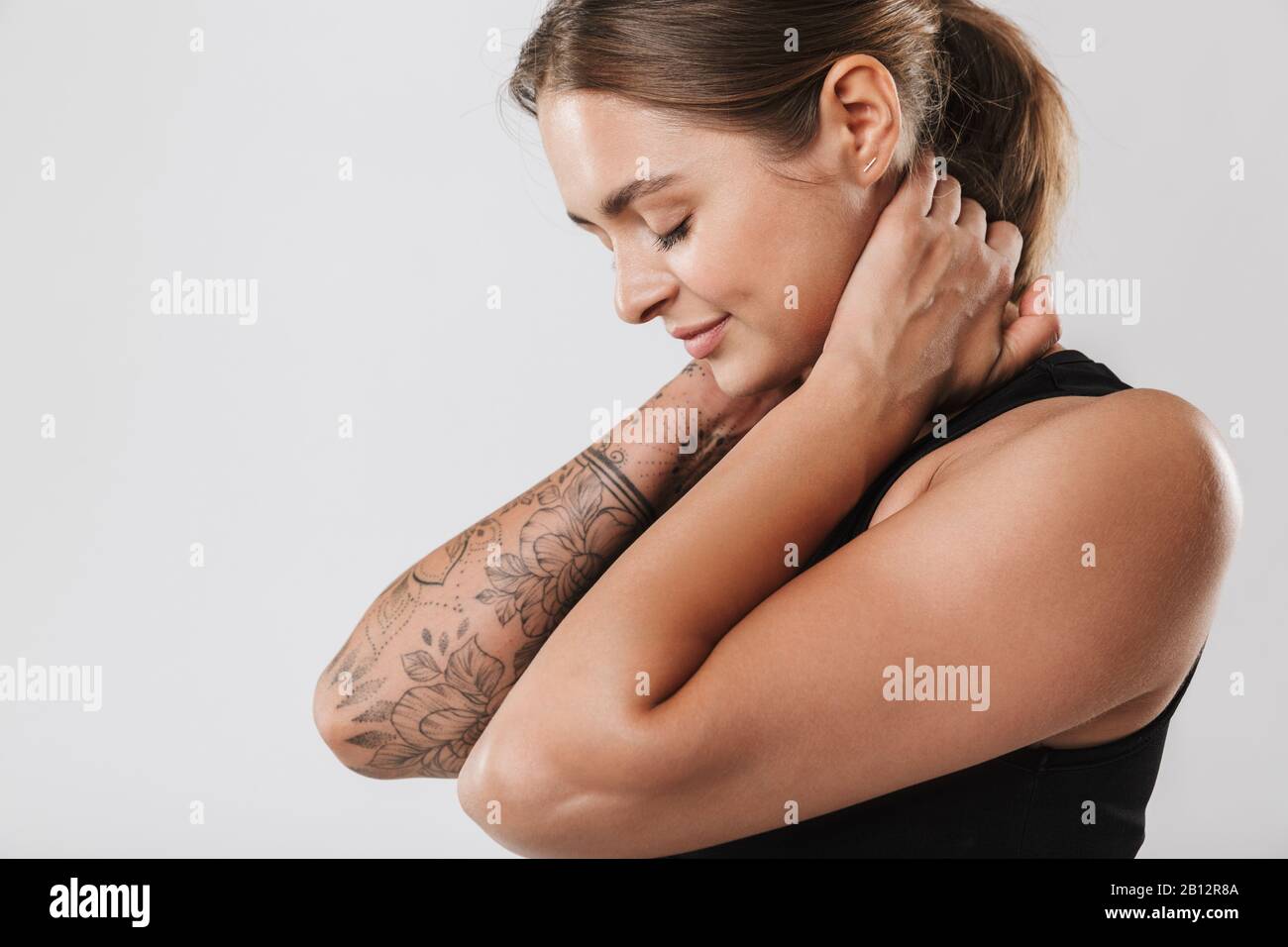 Image of attractive young woman in sportswear touching her neck while ...