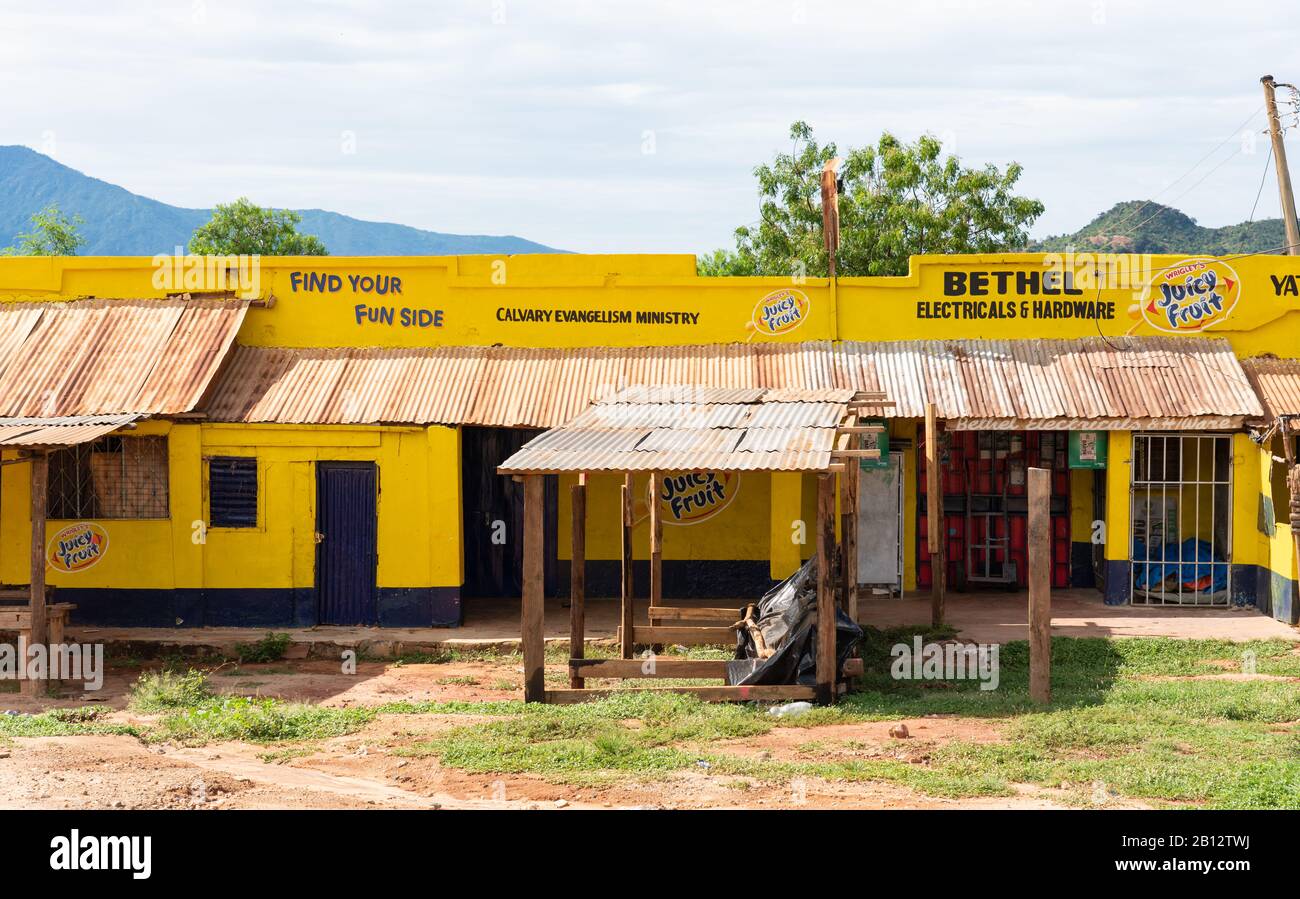 Bright yellow painted shop fronts along the main highway through Voi in Southern Kenya Stock Photo