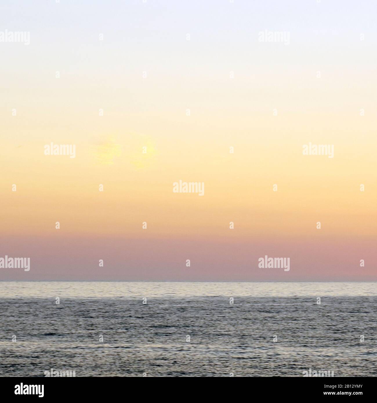 Colour photograph of summer sun setting on the horizon of the Irish Sea taken at Penbryn seafront in Cardigan Bay south west Wales Stock Photo