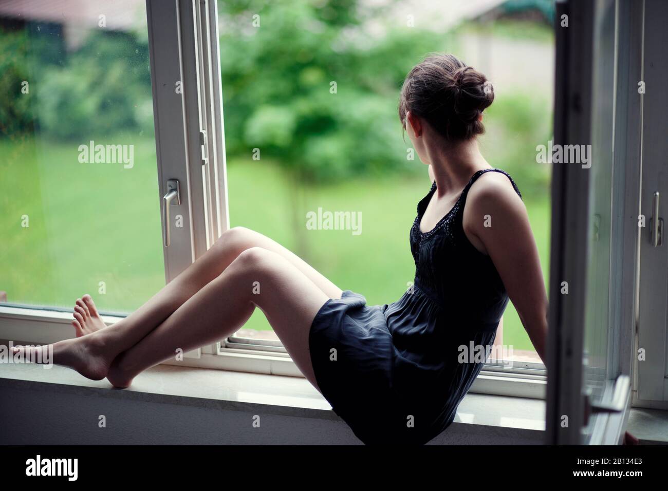 Young woman sitting on a window sill Stock Photo Alamy