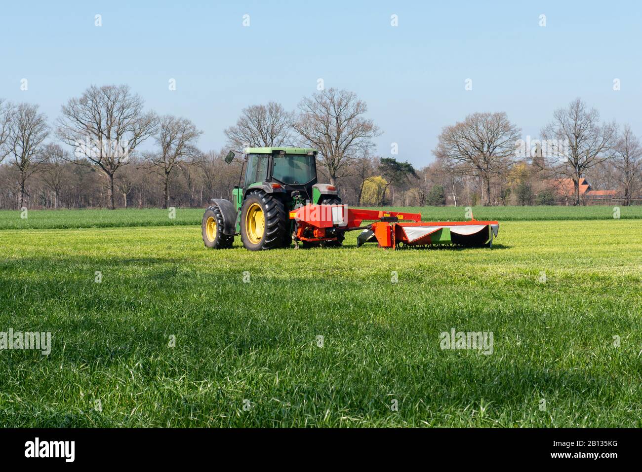 Tractor with mower-conditioner on a partially mown meadow Stock Photo