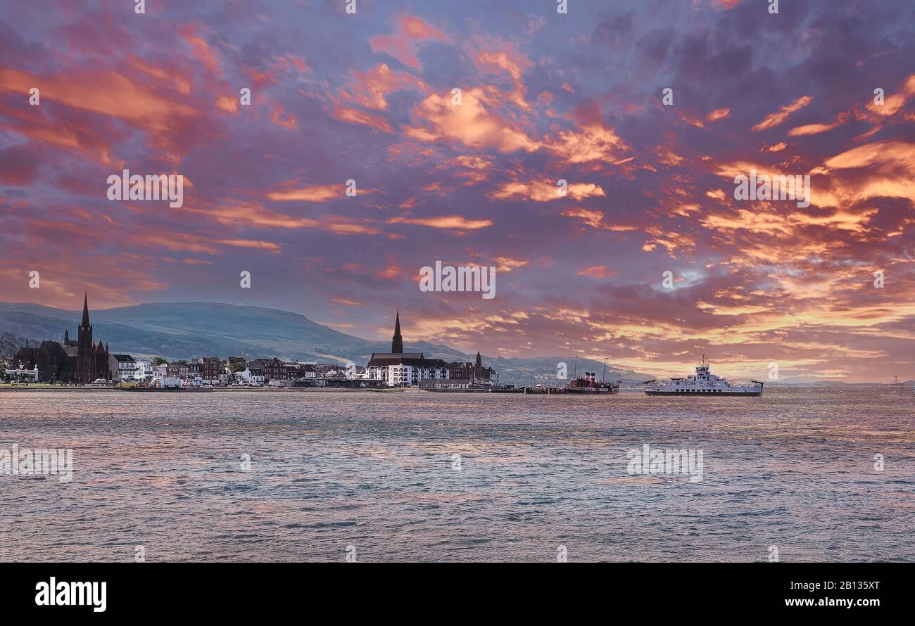 The local car ferry berthing at largs in Ayrshire. The Paddle steamer can be seen in the back ground all at sunset with blazing red skys. Stock Photo