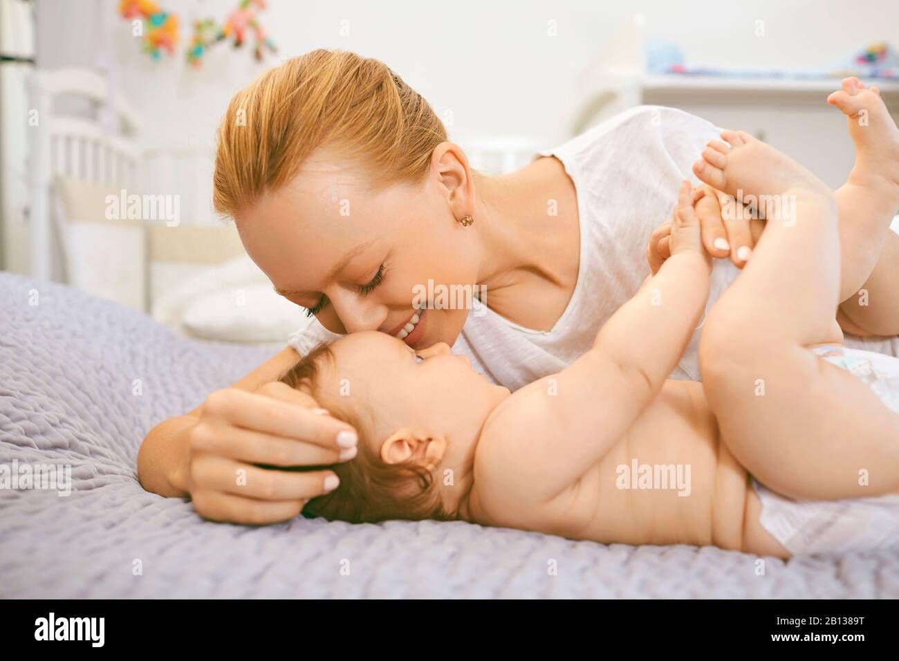 Mothers Day. Mother hugging her baby lying on a bed Stock Photo