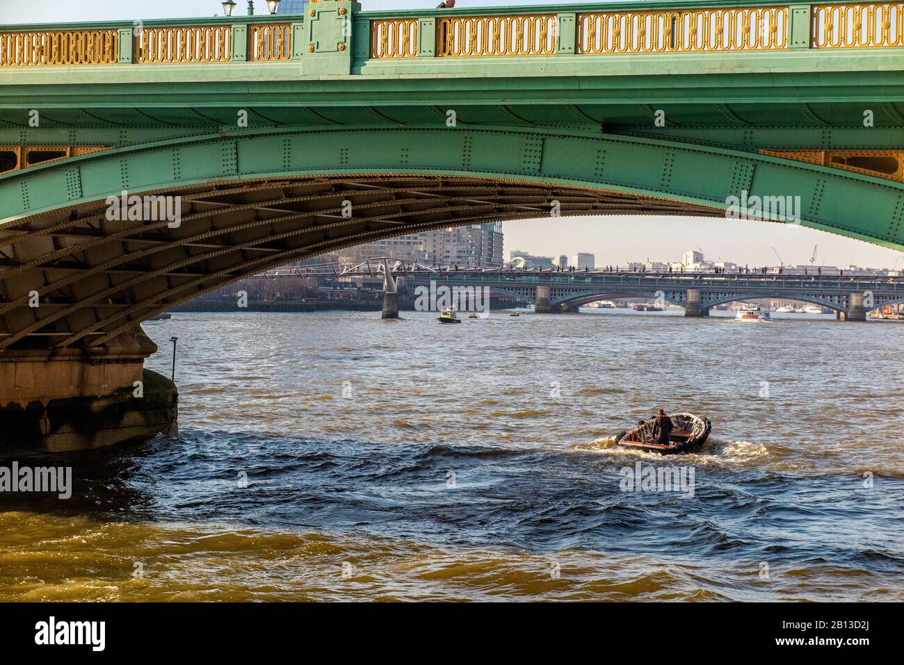 A small vessel passes underneath Southwark Bridge in London Stock Photo
