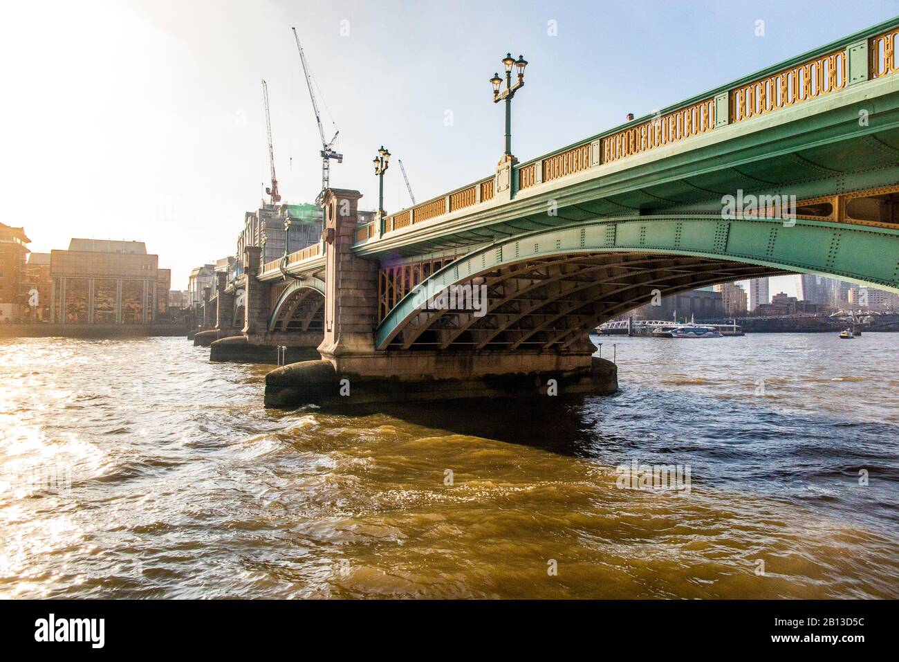 A small vessel passes underneath Southwark Bridge in London Stock Photo