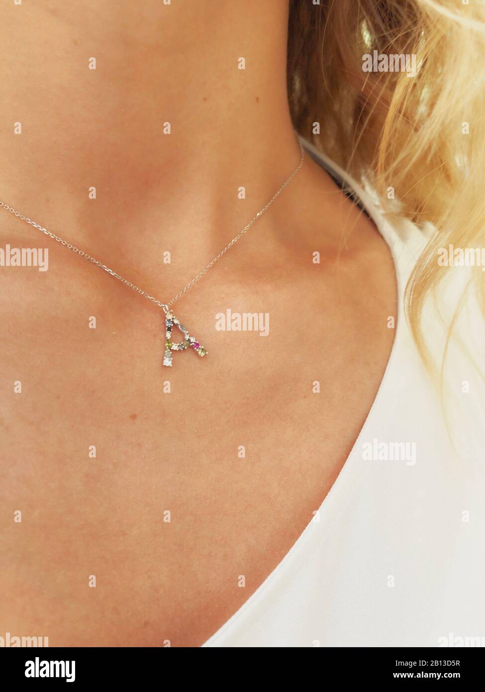Silver initial necklace on tan skin lady's neck Stock Photo Alamy