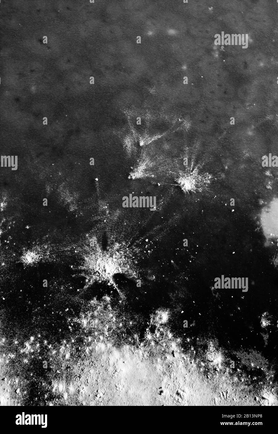 Bright white snow powder bursts dropped on dark gray and black ice