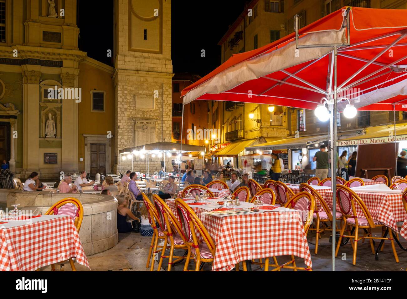 The lively Place Rossetti square late at night as tourists and French enjoy an Italian sidewalk cafe alongside the Nice Cathedral. Stock Photo