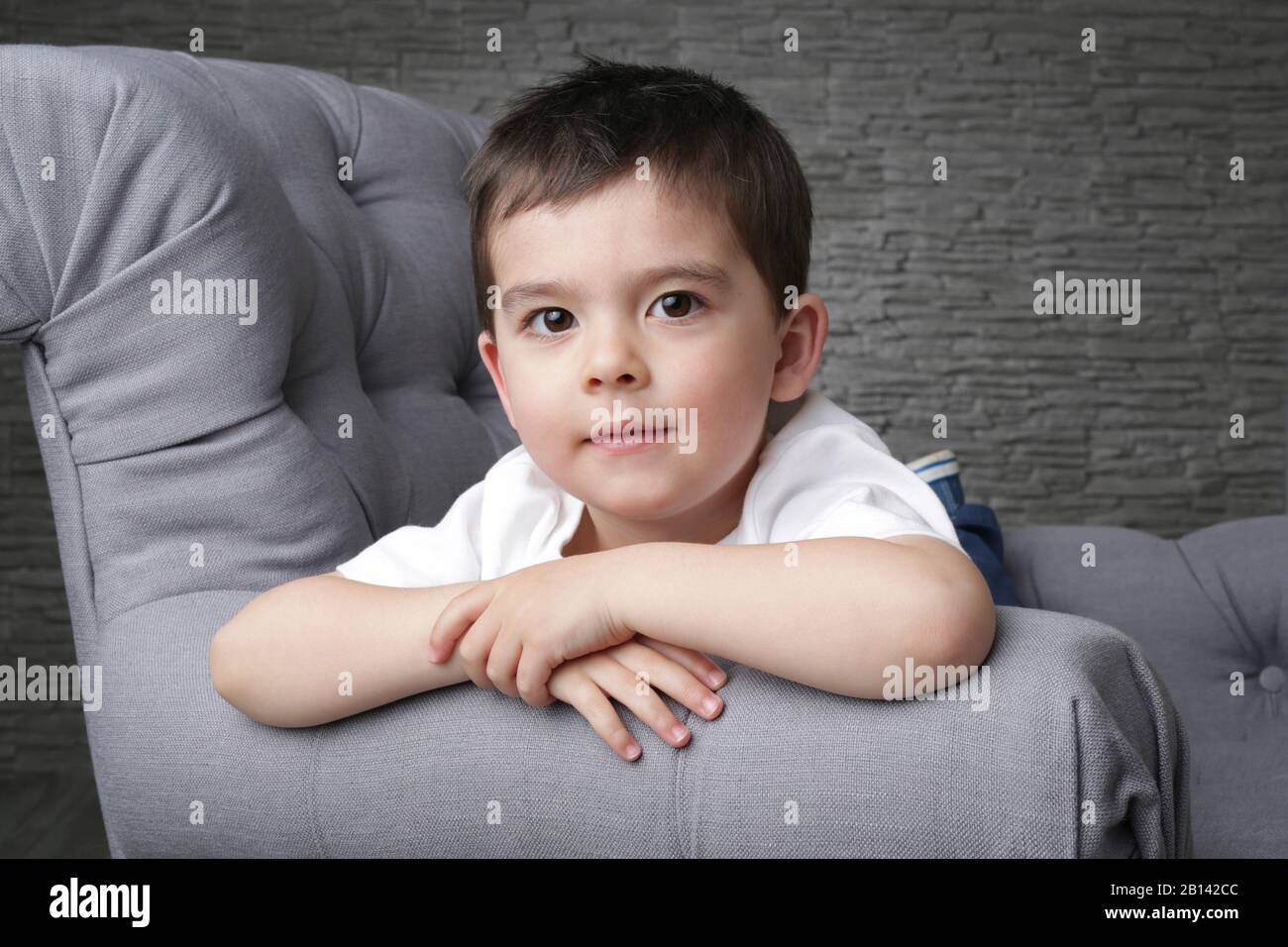 Caucasian child, boy, 3-4 year old, sitting on settee, holding in hand a  plastic cup and drinking from it while watching something in front Stock  Photo - Alamy