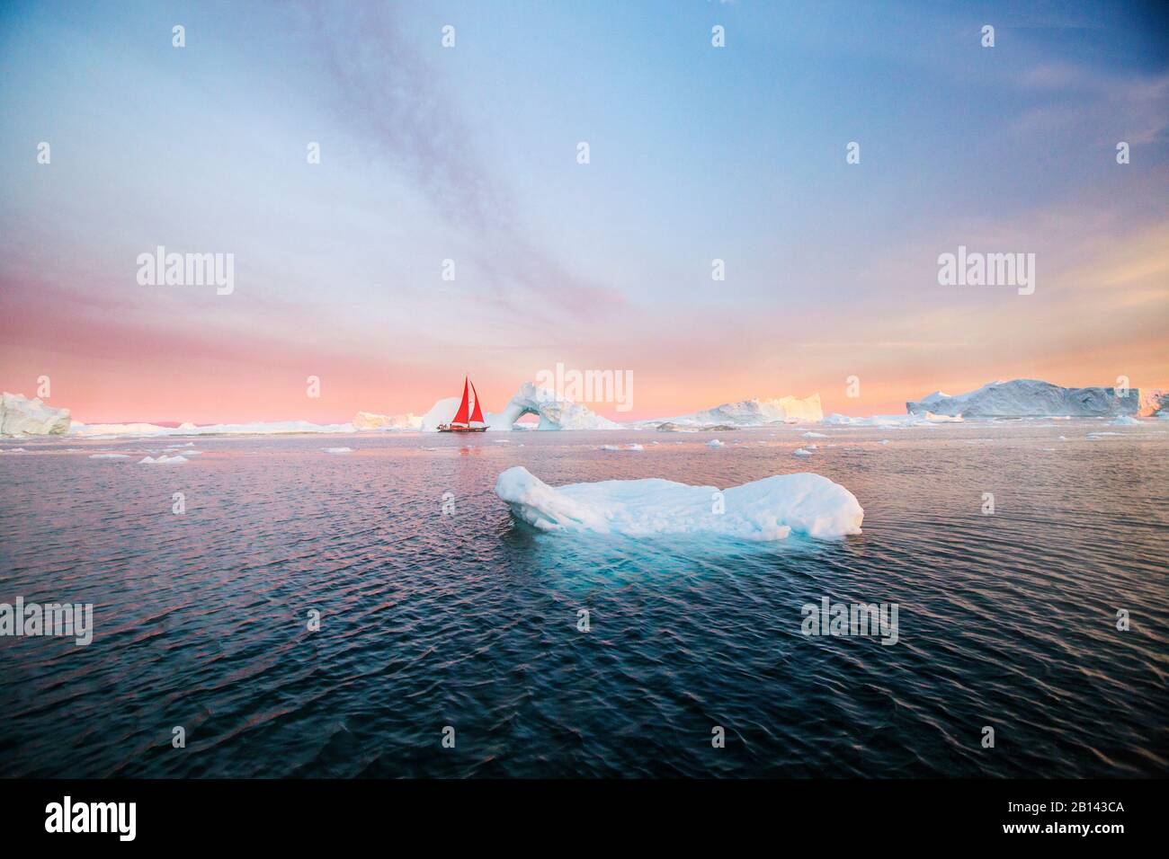 Icebergs and sailboat in Disko Bay on Midsummer, Greenland Stock Photo