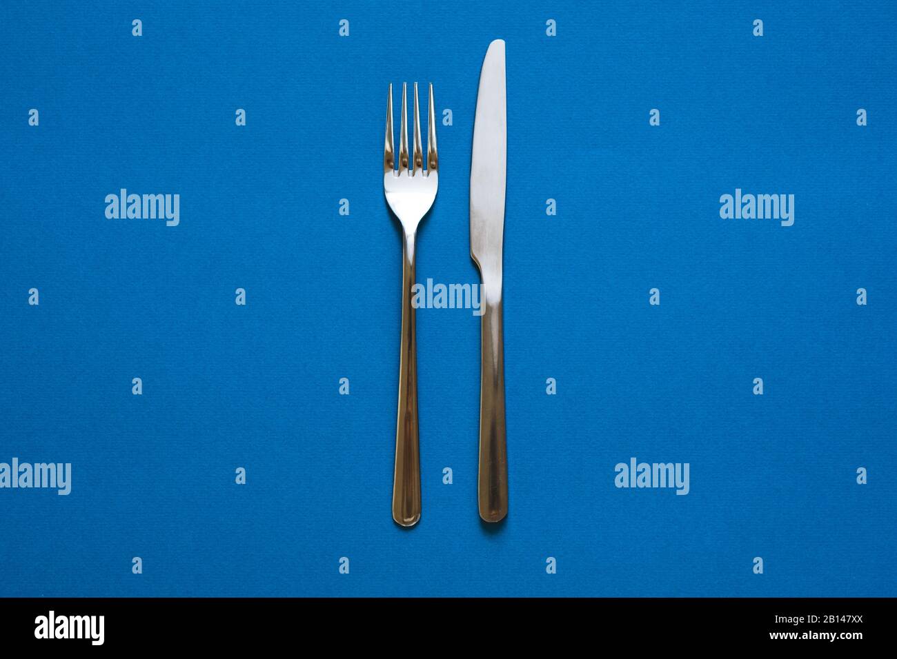 Fork and knife isolated on blue background.  Stock Photo