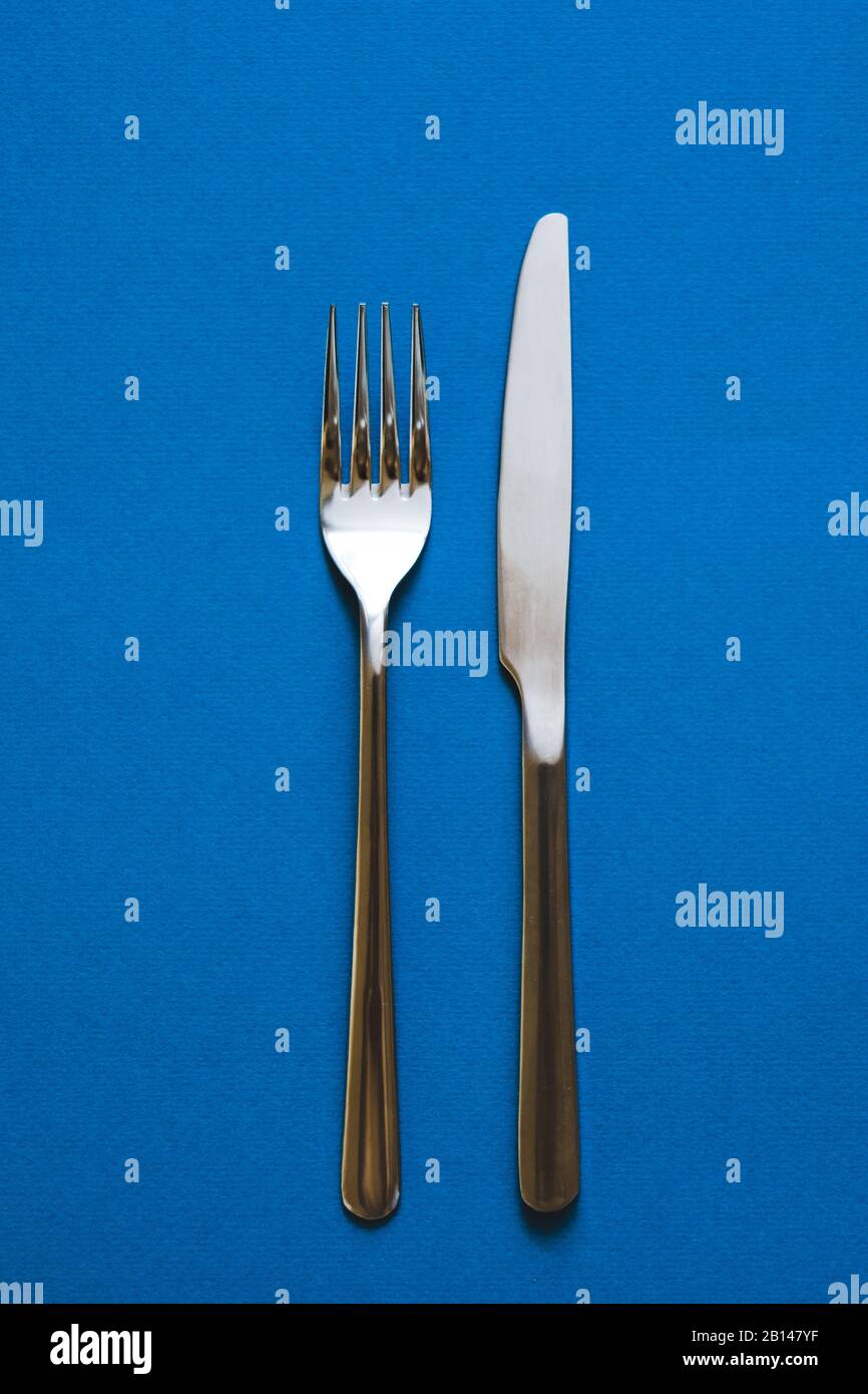 Fork and knife isolated on blue background.  Stock Photo