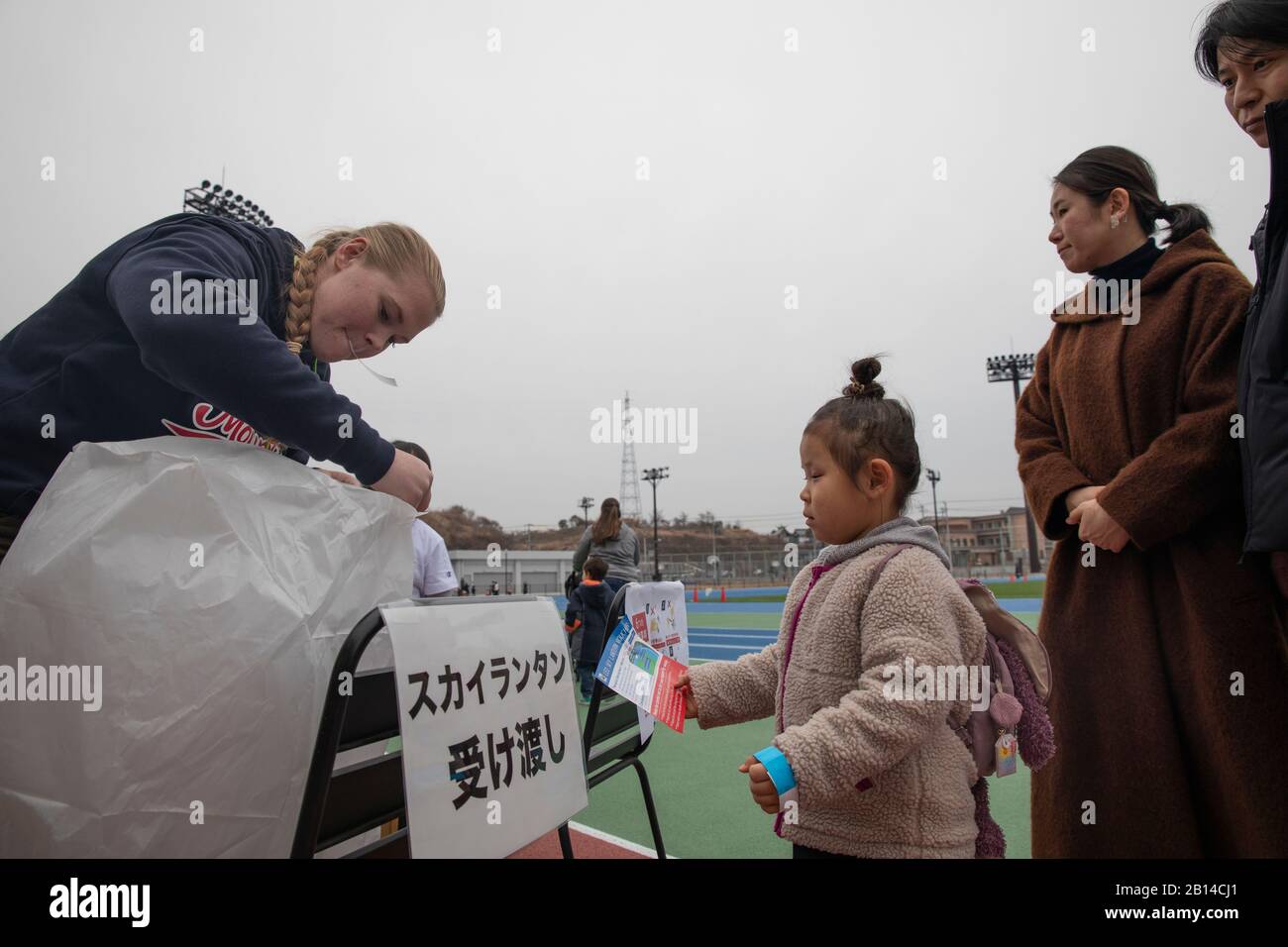 U.S. Marine Corps Sgt. Sheridan Lewis, a basic intelligence Marine with Marine Wing Support Squadron (MWSS) 171, helped a local Japanese child attach a paper to a sky lantern in Iwakuni City, Japan, March 3, 2019. Lewis and other service members volunteered in the event that was held by the Blue Art Project, a non-profit organization that is dedicated to people with developmental disorders. (U.S. Marine Corps photo by Cpl. Andrew Jones) Stock Photo