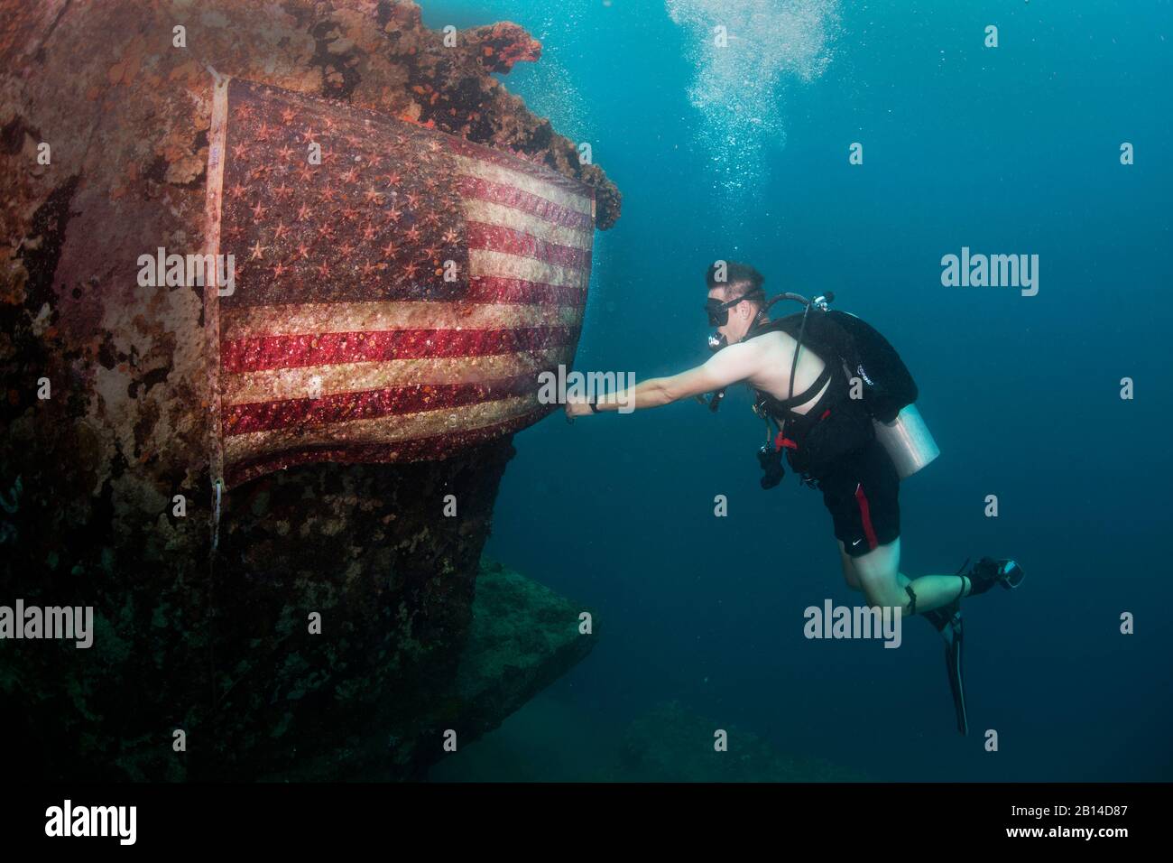 A U.S. Navy master chief petty officer assigned to Explosive Ordnance Disposal (EOD) Group 1 fixes an American flag on the American Tanker, a sunken concrete barge used to transport fuel during WWII, in Guam’s Apra Harbor June 21, 2017. U.S. Navy EOD is the world's premier combat force for countering explosive hazards and conducting expeditionary diving and salvage. (U.S. Navy Combat Camera photo by Mass Communication Specialist 3rd Class Alfred A. Coffield) Stock Photo