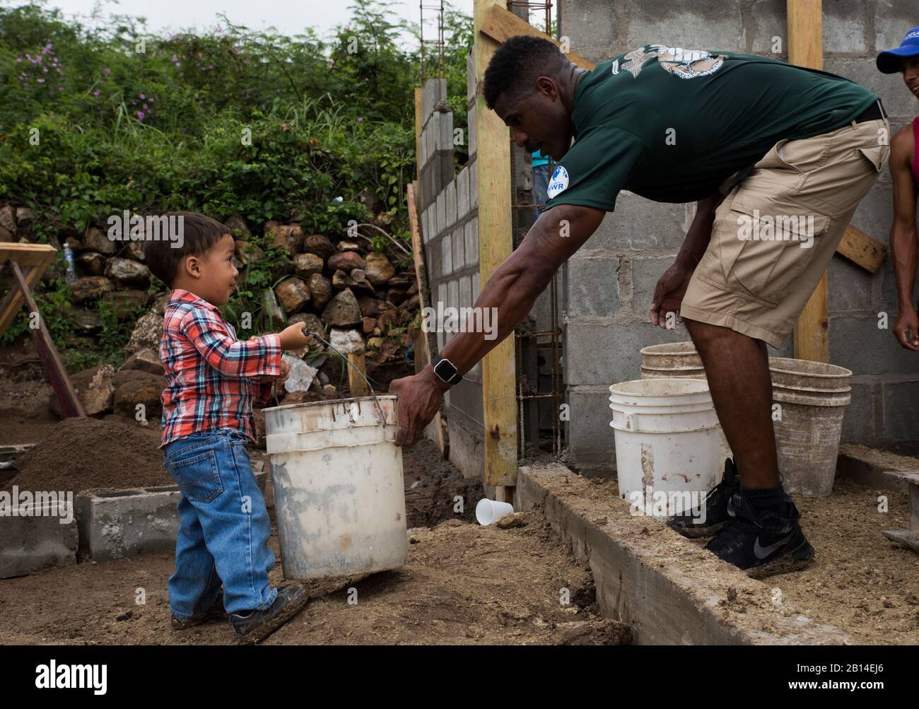 U.S. Marine Corps Sgt. Antoine D. Coleman, the armory chief with the Command Element, Special Purpose Marine Air-Ground Task Force - Southern Command, helps a child carry a bucket of gravel during a community relations event in La Paz, Honduras, Oct. 25, 2017. Partnered with Habitat for Humanity, the Marines worked to build the foundation of a house for a local family. The Marines and sailors of SPMAGTF-SC are deployed to Central America to conduct security cooperation training and engineering projects with their counterparts in several Central American and Caribbean nations. (U.S. Marine Corp Stock Photo