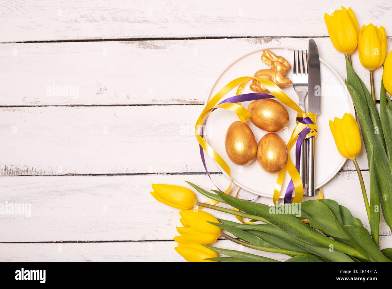 Easter background with blue and white eggs in nest and yellow tulips ...