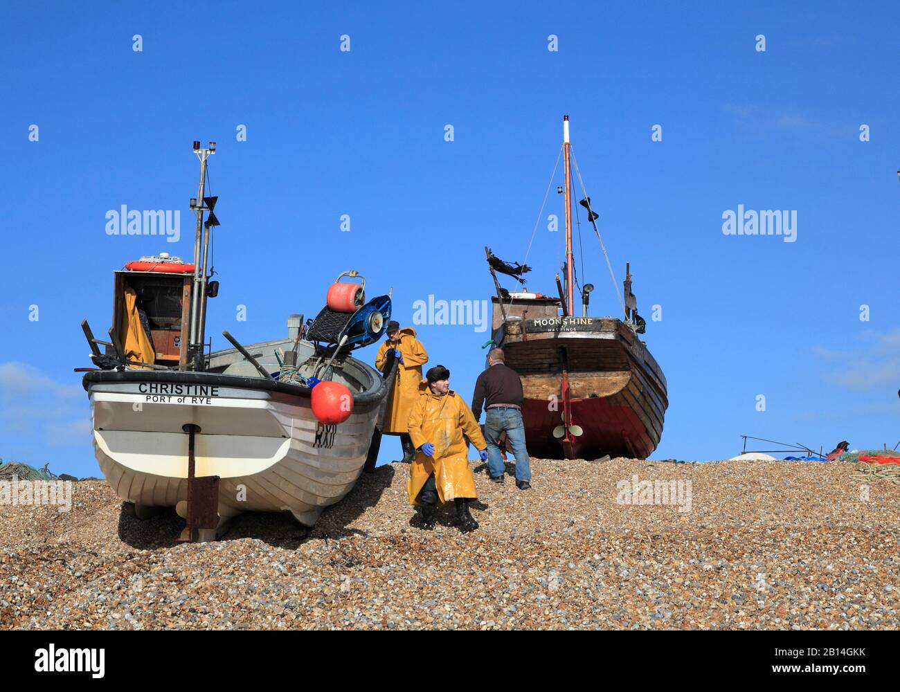Hastings fishermen in yellow oilskins landing fishing boat  on the Old Town Stade fishermen's beach, Rock-a-Nore, East Sussex, UK Stock Photo