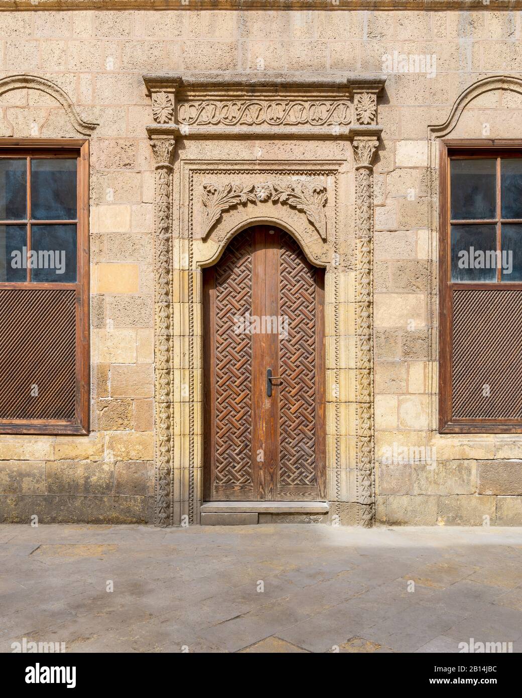Facade of old abandoned stone decorated bricks wall with arched wooden ...