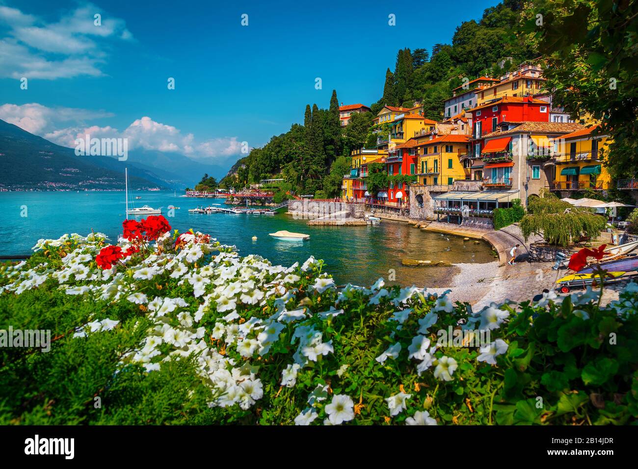 Flowery garden on the lake shore and stunning view with colorful buildings. Moored boats and motorboats in the bay, lake Como, Varenna, Italy, Europe Stock Photo