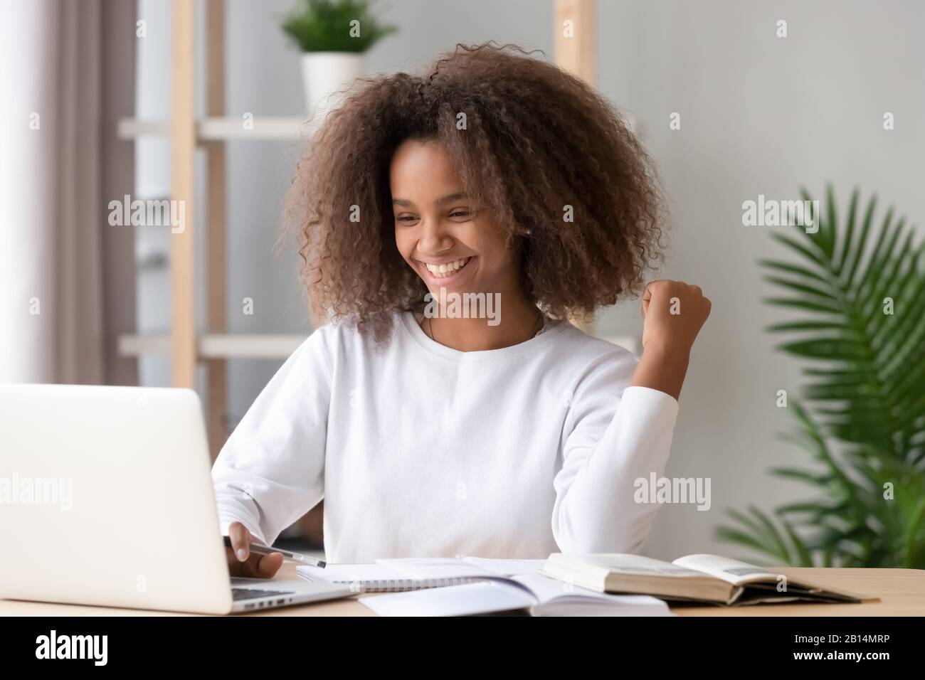 Excited overjoyed african teen girl student winner looking at laptop ...