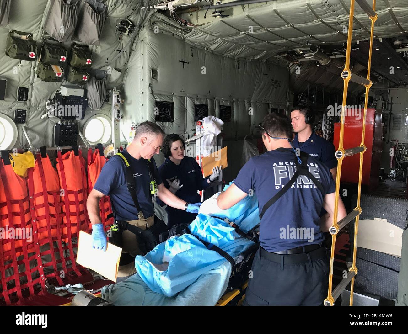 U.S. Navy Petty Officer 3rd Class Rena Gilbertson, a health services technician aboard an Air Station Kodiak HC-130J Hercules aircraft, works with Anchorage emergency medical services personnel to transfer a woman to higher medical care in Anchorage, Alaska, August 3, 2019. Air Station Kodiak aircrews medevaced the woman and her husband from St. Paul Island, Alaska, to Anchorage for further care. (U.S. Coast Guard courtesy photo) Stock Photo