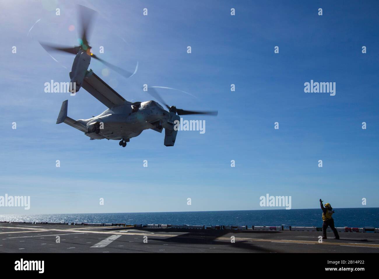 A U.S. Navy sailor with the amphibious assault ship USS Wasp (LHD 1) guides an MV-22B Osprey tiltrotor aircraft with Marine Medium Tiltrotor Squadron 265 (Reinforced), 31st Marine Expeditionary Unit, to land during flight operations aboard the Wasp in the Coral Sea, July 15, 2019. Wasp, flagship of the Wasp Amphibious Ready Group, with embarked 31st MEU, is currently participating in Talisman Sabre 2019 off the coast of Northern Australia. A bilateral, biennial event, Talisman Sabre is designed to improve U.S. and Australian combat training, readiness and interoperability through realistic, re Stock Photo